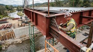 Ironworker bolting steel bridge girders during fabrication